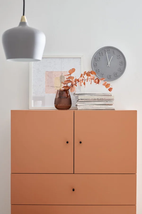 Pomarańczowa komoda w jasnym, minimalistycznym wnętrzu.